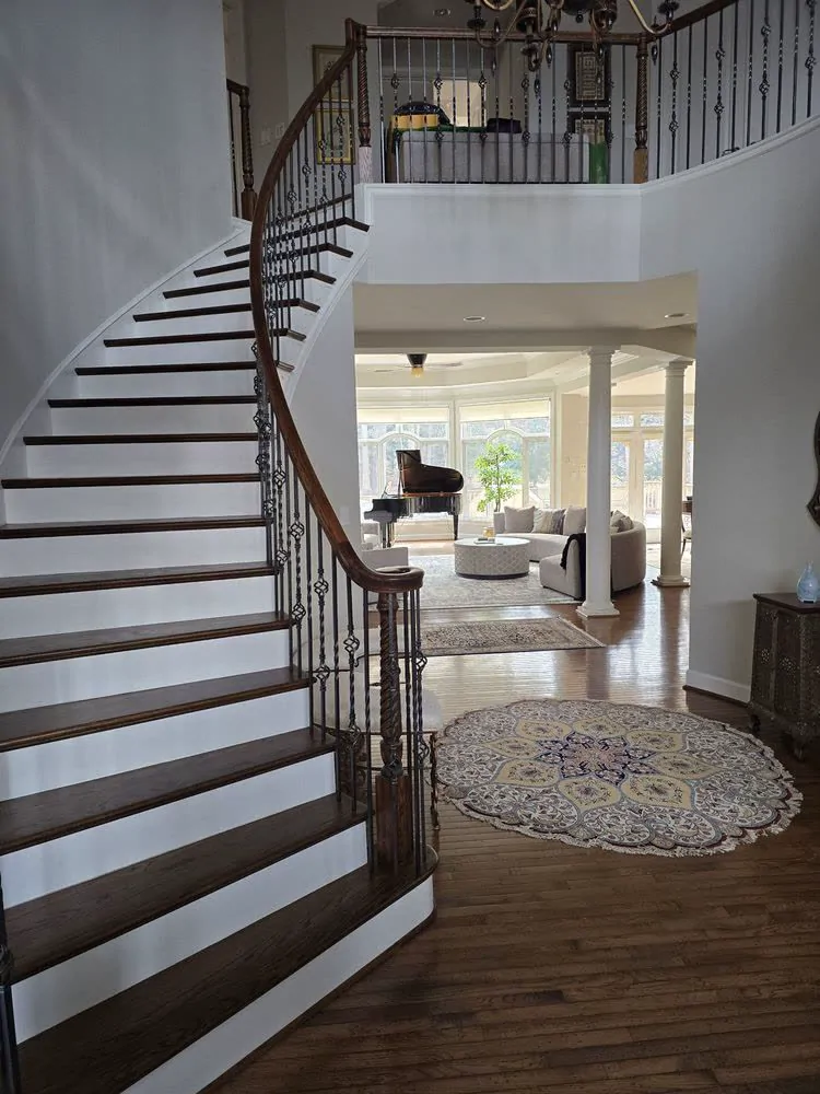 A foyer with a curved staircase and a patterned rug after a Pura Clean visit